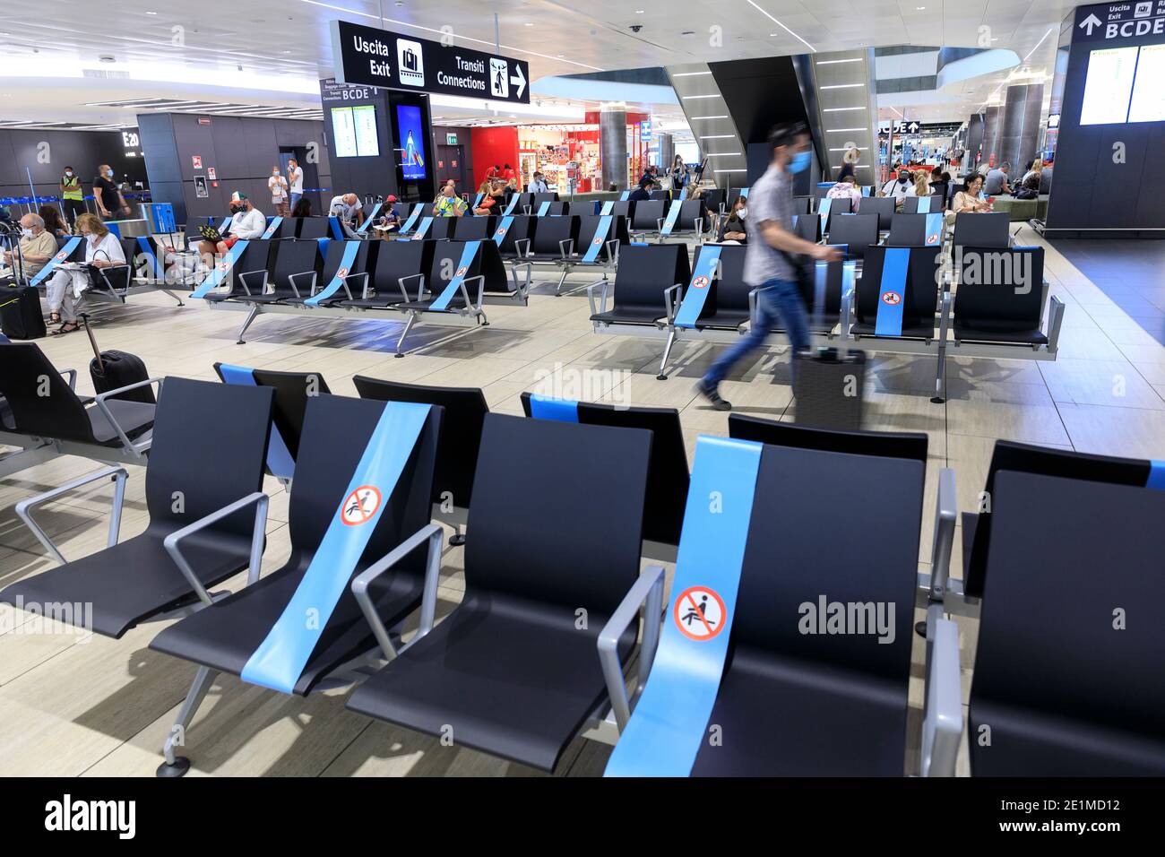 Der Flughafen Leonardo da Vinci in Fiumicino, Italien: Passagiere, die im Terminal auf ihren Flug warten. Einige der Sitze sind wegen des i blockiert Stockfoto