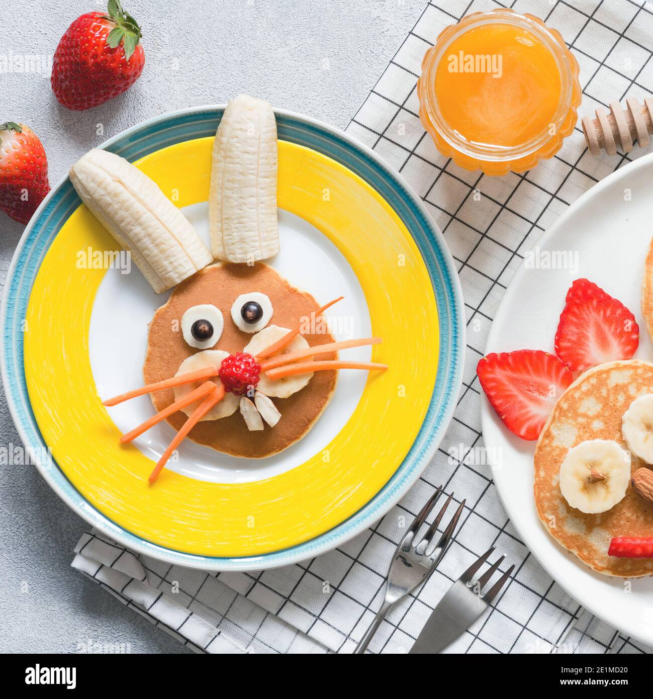 Kreatives Frühstück für Kinder zu Ostern. Hase-förmige süße Pfannkuchen mit Früchten, Beeren und Honig. Babynahrung Stockfoto
