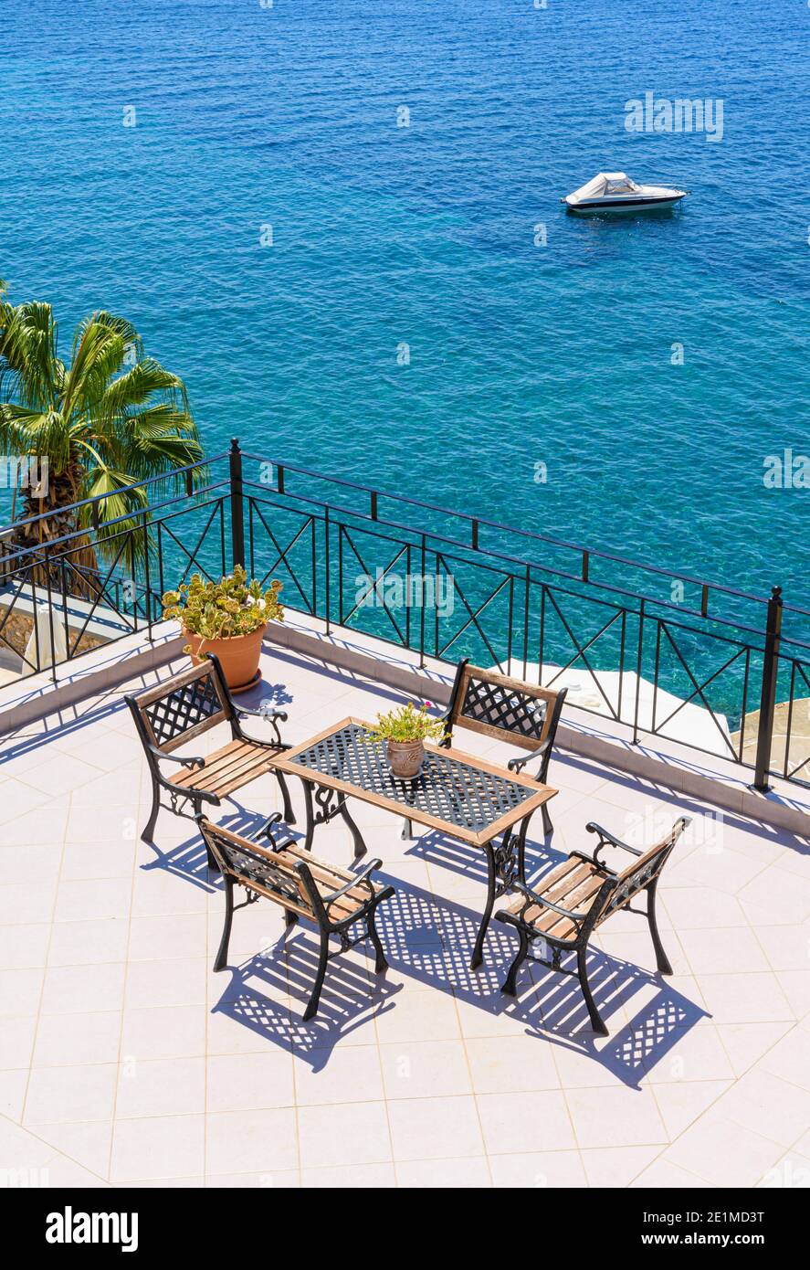 Blick auf die Ägäis über Tisch und Stühlen auf einem Balkon im Ferienort Masouri, Kalymnos, Dodekanes, Griechenland Stockfoto