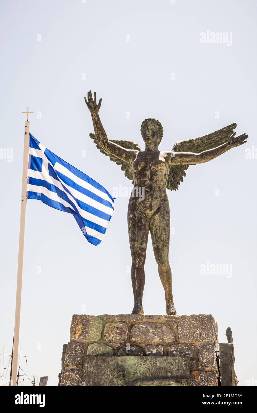 Geflügelte Nike Statue neben der griechischen Flagge in Pothia Town, Kalymnos, Dodekanes, Griechenland Stockfoto