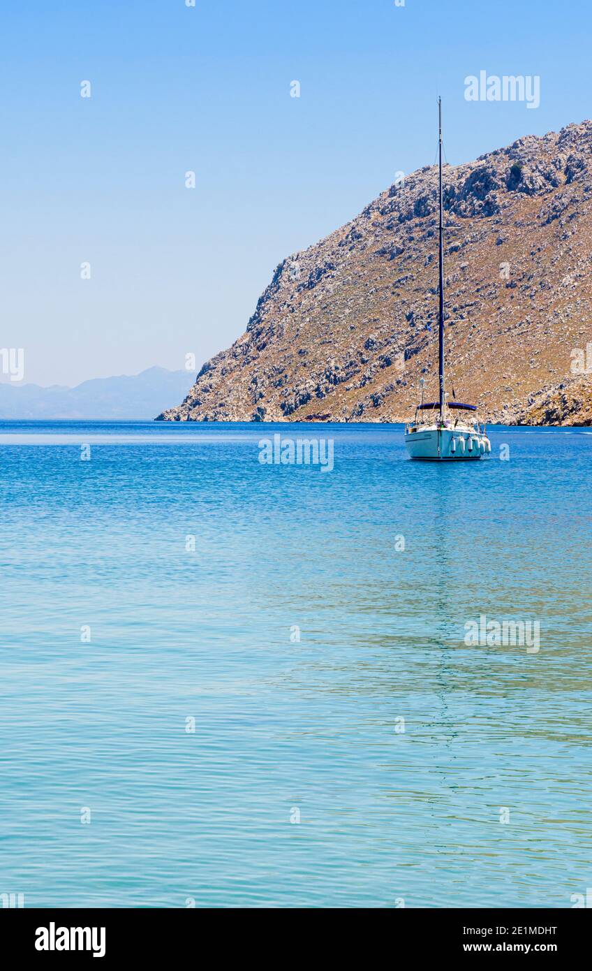 Yacht vor Anker in den ruhigen Gewässern der Pedi Bay, Symi Island, Dodekanes, Griechenland Stockfoto
