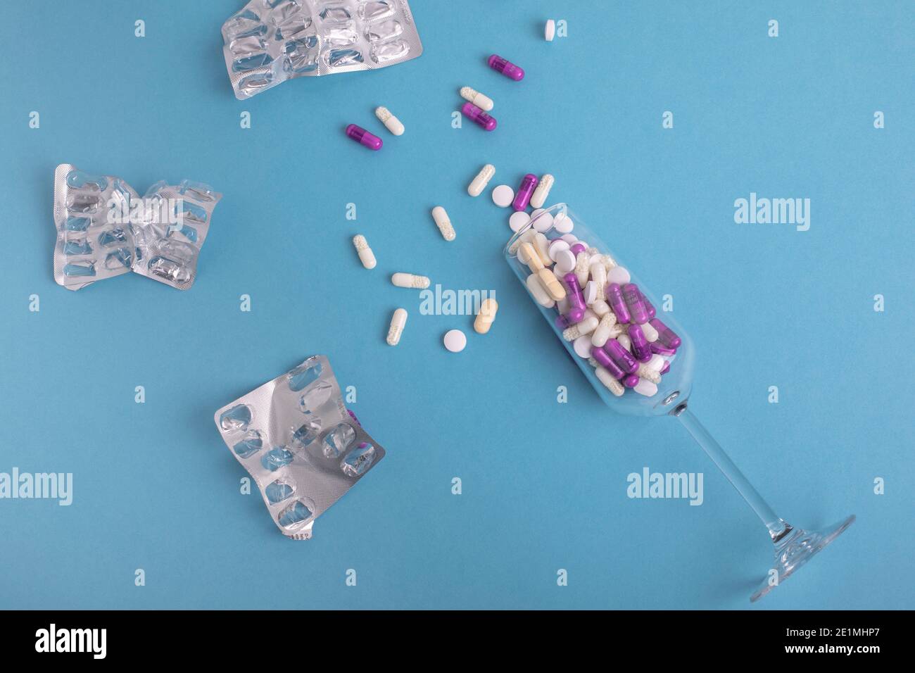 Sektglas gefüllt mit Pillen auf blauem Hintergrund. Psychische Gesundheit einfaches Konzept Bewusstsein Stockfoto