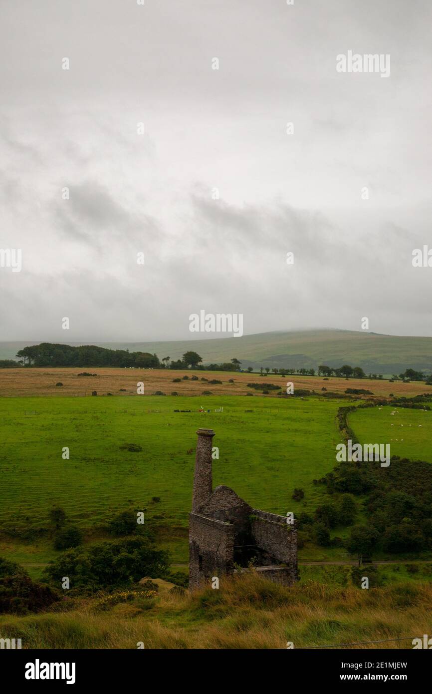 Verlassenes Maschinenhaus in der Cornish Tin Mine, umgeben von grünen Feldern und grau bewölkter Landschaft (Winter), Cornwall, England Stockfoto