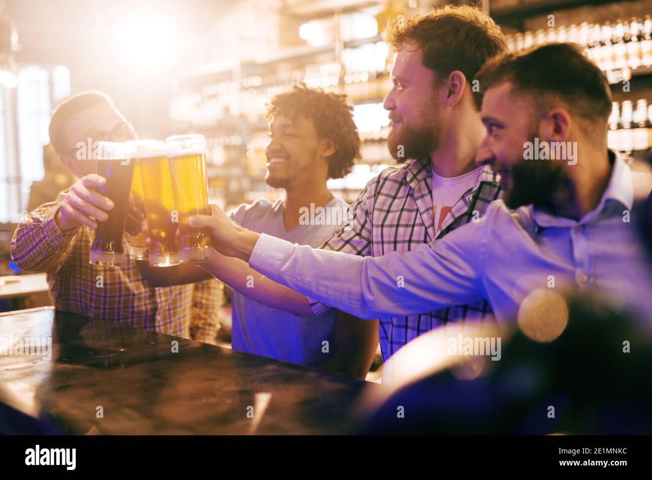 Eine Gruppe von vier Freunden, die an der Bar anstoßen. Pub-Interieur. Stockfoto