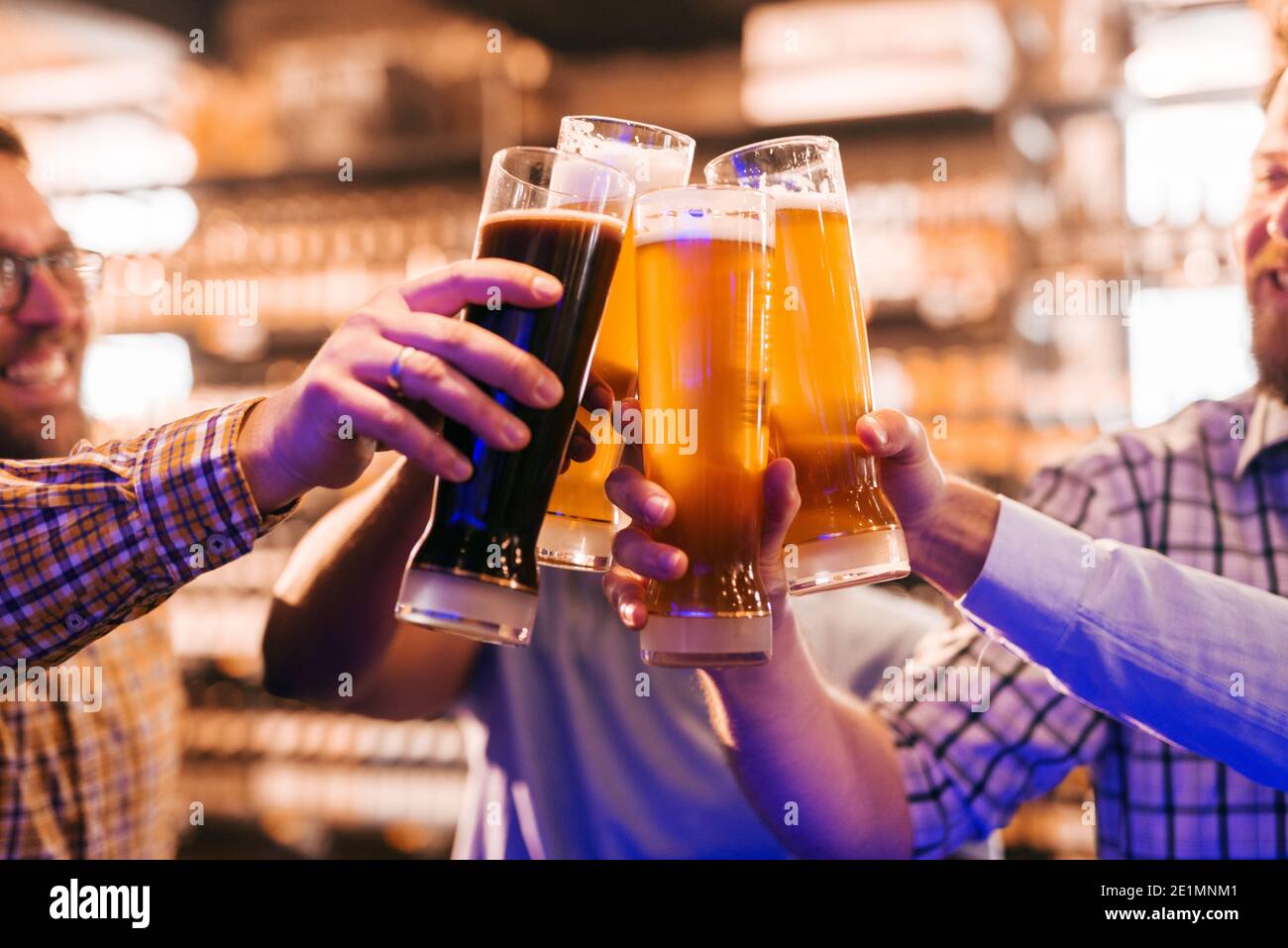 Nahaufnahme von Freunden, die einen Toast mit Bier machen. Pub-Interieur. Stockfoto