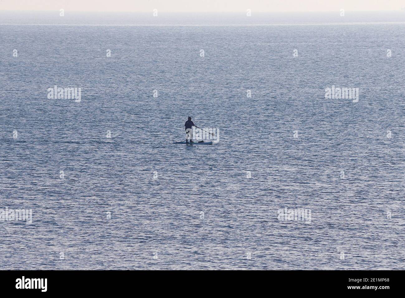 Hove, East Sussex, Großbritannien. Januar 2021, 08. UK Wetter: Ein kühler, aber heller und sonniger Tag an der Strandpromenade und am Strand als Menschenmassen nutzen einige mit Gesichtsmasken das schöne Wetter. Ein einflüggleres Paddelboot, das auf See boarder. Foto-Kredit: Paul Lawrenson/Alamy Live Nachrichten Stockfoto