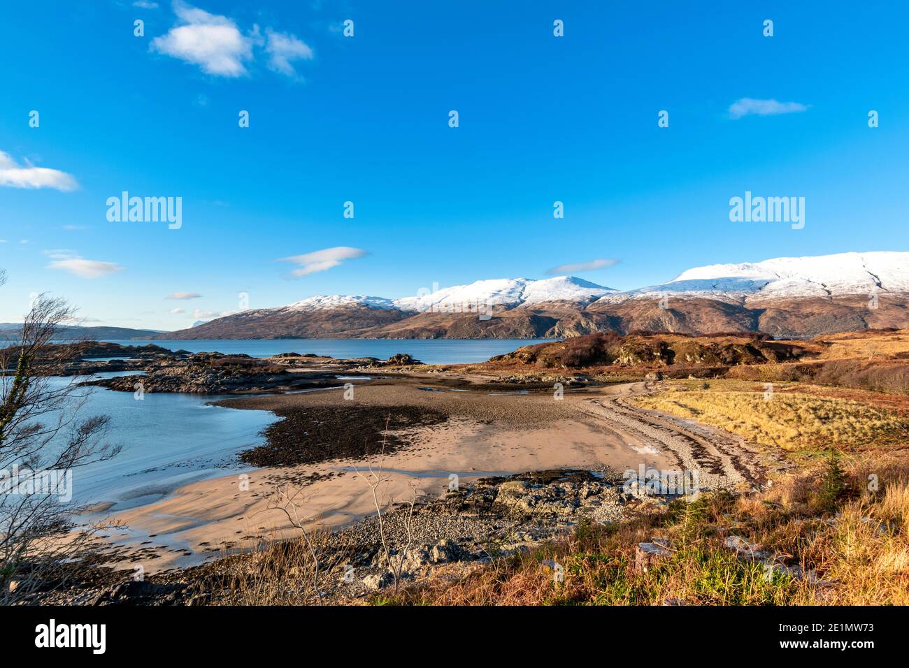 SCHOTTLAND WESTKÜSTE HIGHLANDS KINTAIL SANDAIG UND INSELN DER SAND STRAND IN SONNENLICHT BEI EBBE SCHNEE AUF DEN BERGEN Stockfoto