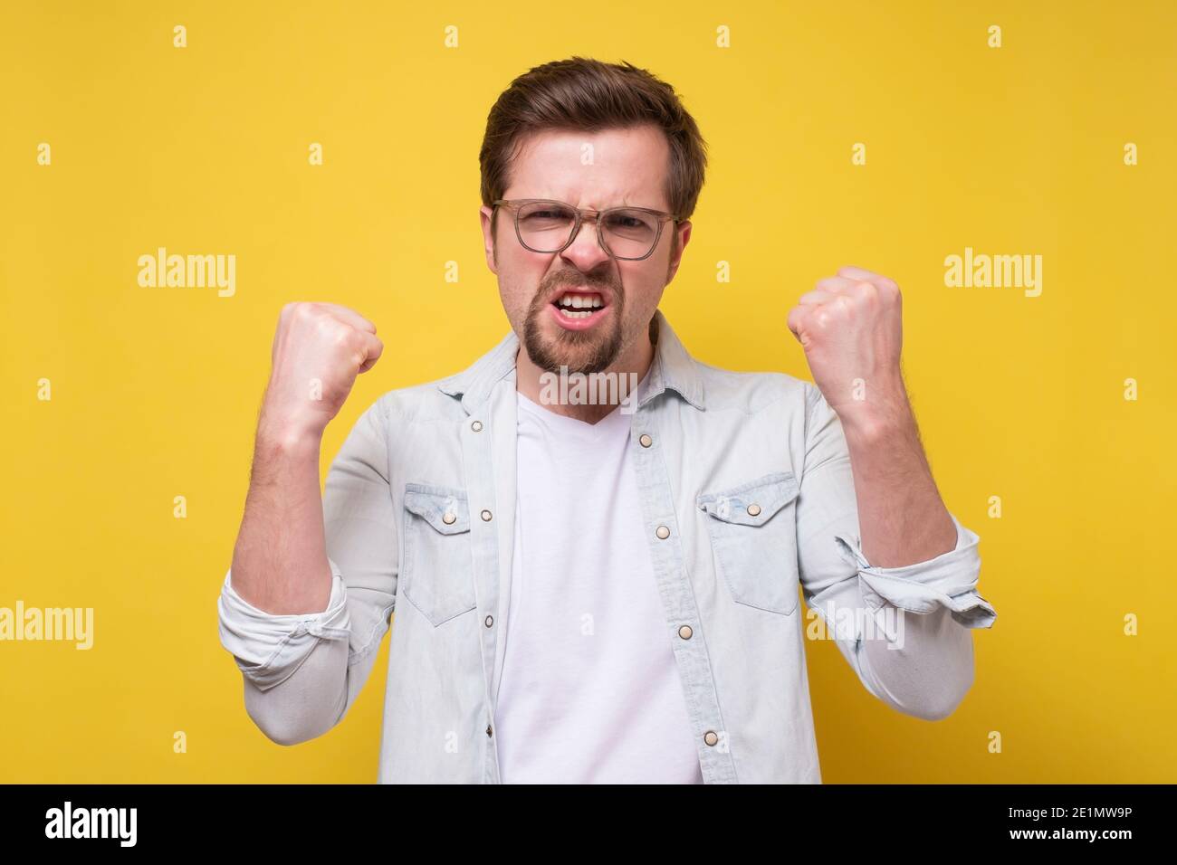 Hübscher Mann, der wütend und verrückt ist, die Faust zu erheben, frustriert und wütend. Wut und aggressives Konzept. Stockfoto