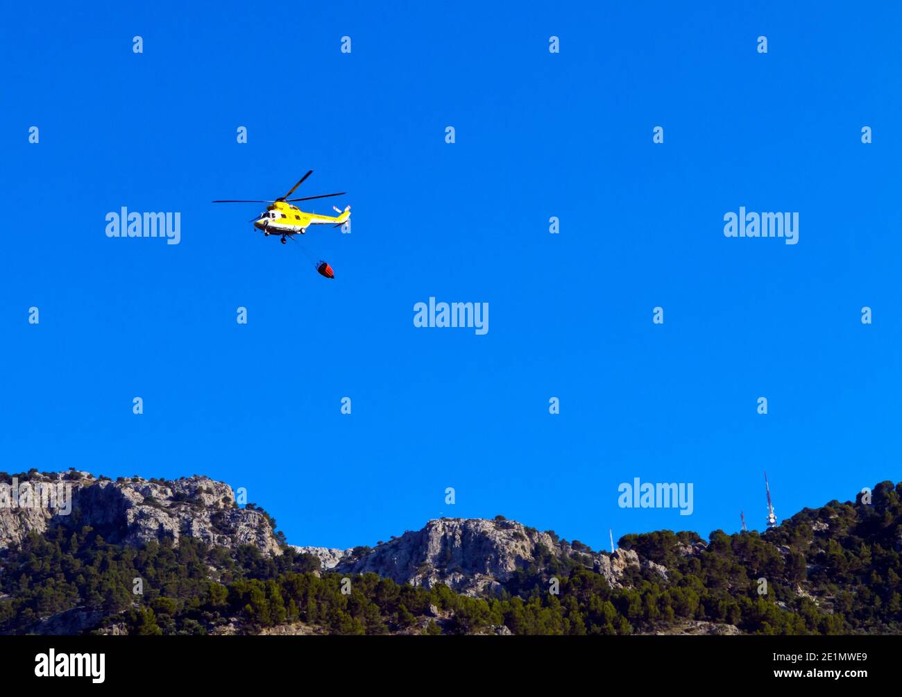 Hubschrauber mit Wasser, um einen Waldbrand zu löschen Die Serra de Tramuntana Bergkette im Nordwesten Mallorcas Balearen Spanien Stockfoto