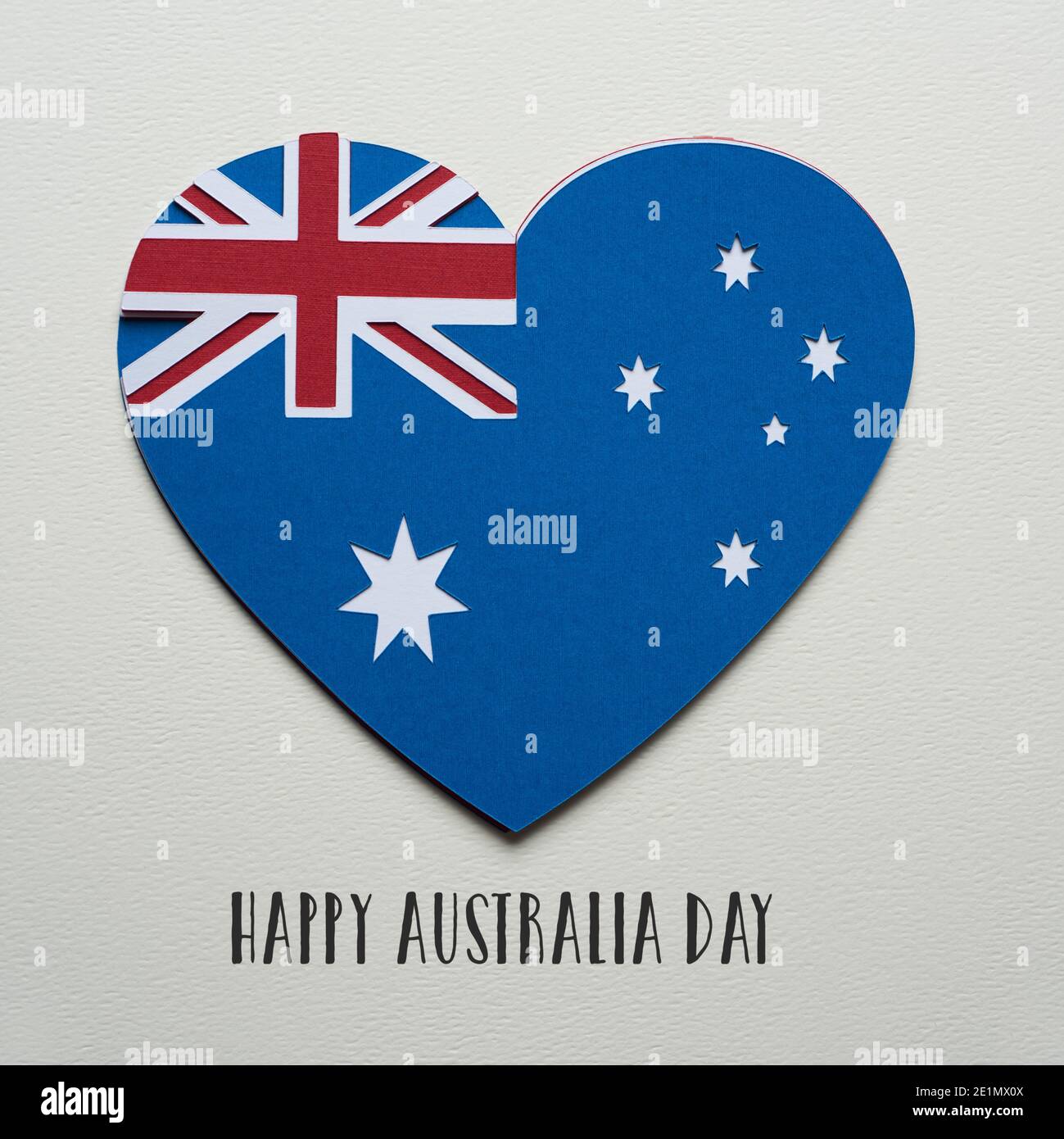 Eine australische Flagge in Form eines Herzens, hergestellt mit Ausschnitten aus Papier in verschiedenen Farben, und der Text Happy australia Day auf einem strukturierten off-white b Stockfoto