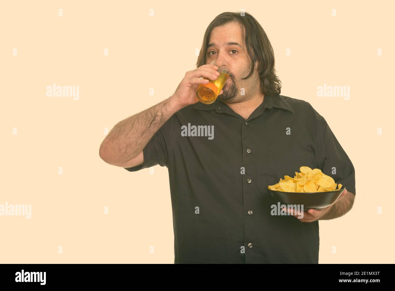 Fat kaukasischen Mann Bier trinken, während Sie Schüssel Chips Stockfoto