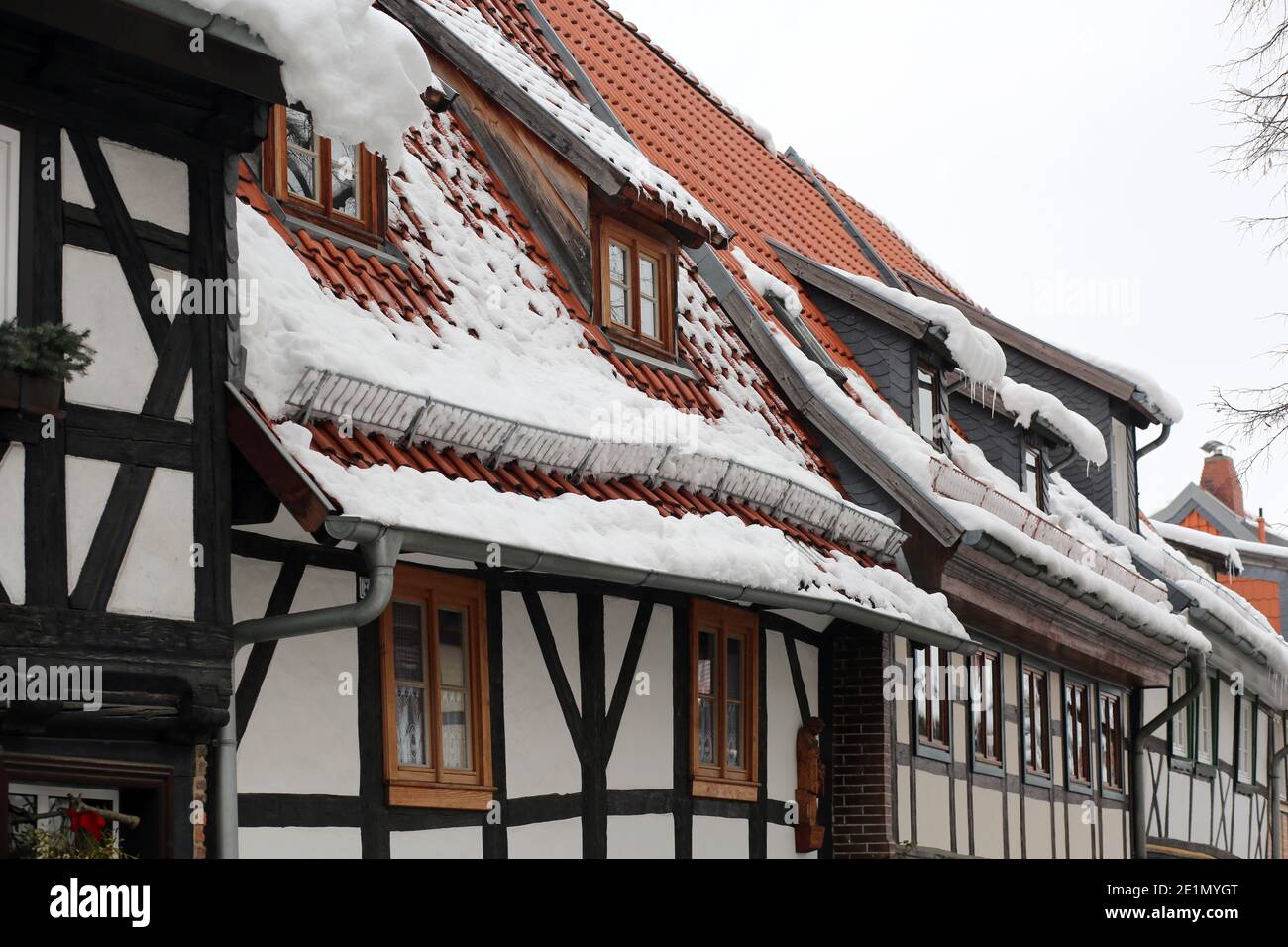 Wernigerode, Deutschland. Januar 2021. Schnee liegt auf den Dächern von Häusern. Mit dem Einsetzen des Tauwetters besteht die Gefahr fallender Schneemassen, auch Dachlawinen genannt. Hausbesitzer verwenden Schilder, um die vorbeifahrenden Menschen auf die Gefahr aufmerksam zu machen. Quelle: Matthias Bein/dpa-Zentralbild/ZB/dpa/Alamy Live News Stockfoto