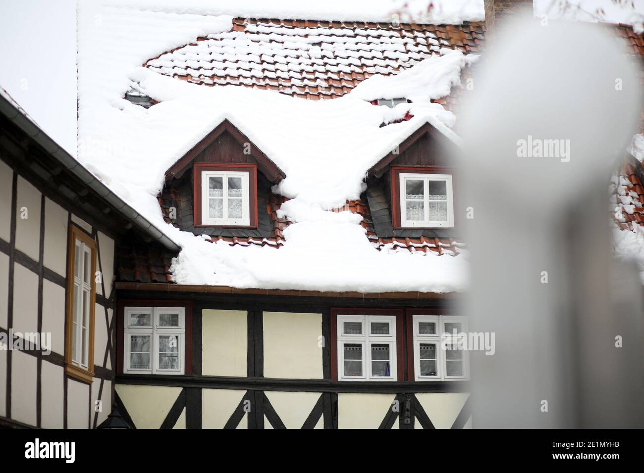 Wernigerode, Deutschland. Januar 2021. Schnee liegt auf den Dächern von Häusern. Mit dem Einsetzen des Tauwetters besteht die Gefahr fallender Schneemassen, auch Dachlawinen genannt. Hausbesitzer verwenden Schilder, um die vorbeifahrenden Menschen auf die Gefahr aufmerksam zu machen. Quelle: Matthias Bein/dpa-Zentralbild/ZB/dpa/Alamy Live News Stockfoto