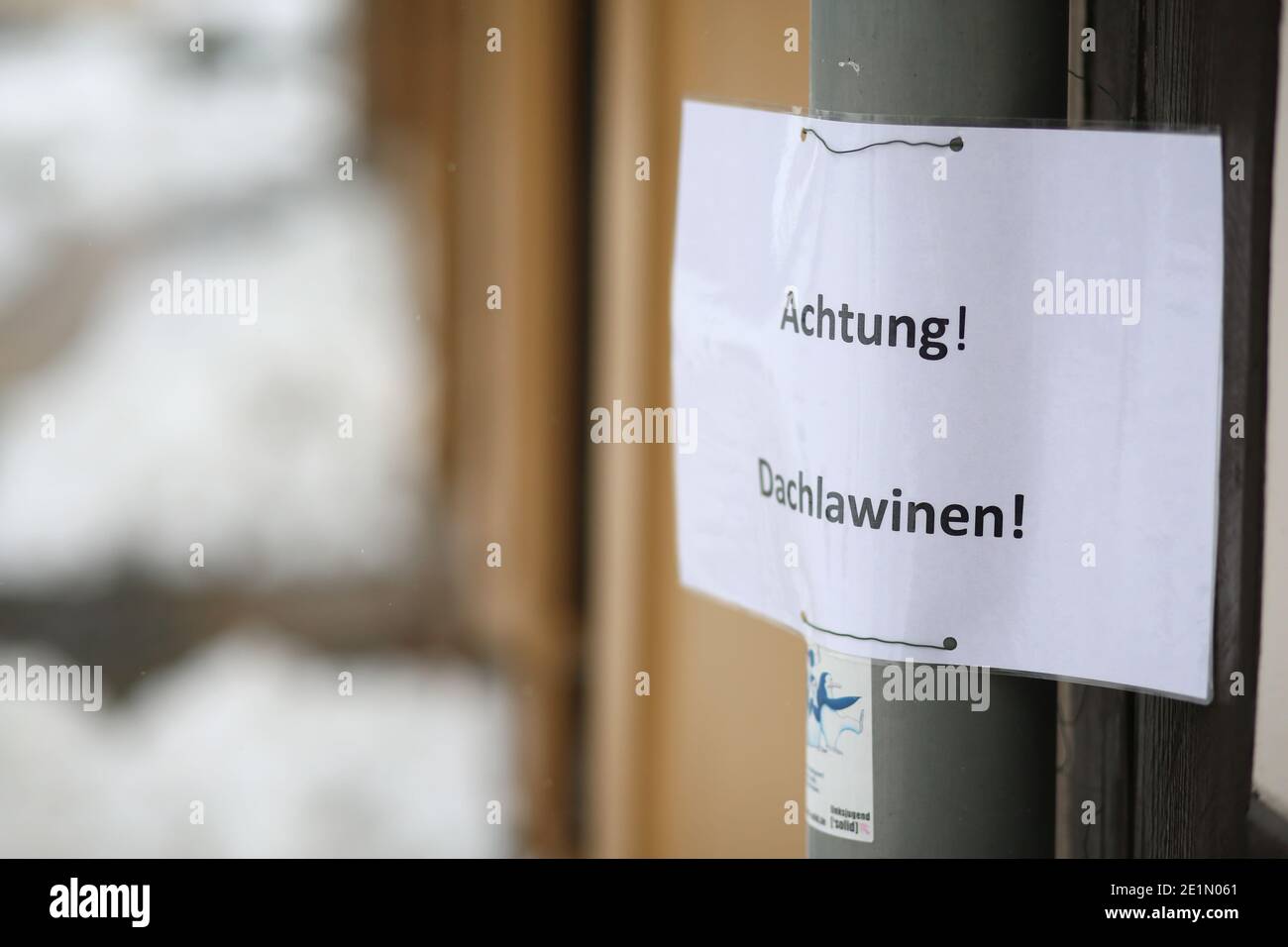Wernigerode, Deutschland. Januar 2021. Schnee liegt auf den Dächern von Häusern. Mit dem Einsetzen des Tauwetters besteht die Gefahr fallender Schneemassen, auch Dachlawinen genannt. Hausbesitzer verwenden Schilder, um die vorbeifahrenden Menschen auf die Gefahr aufmerksam zu machen. Quelle: Matthias Bein/dpa-Zentralbild/ZB/dpa/Alamy Live News Stockfoto