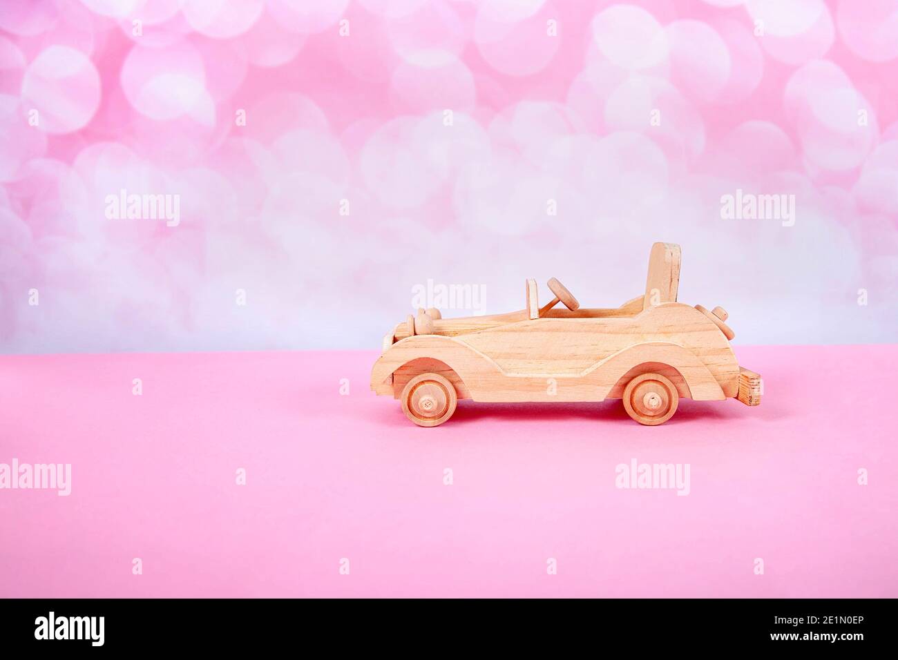 Holz Retro Auto Spielzeug auf einem rosa Hintergrund mit Bokeh Stockfoto