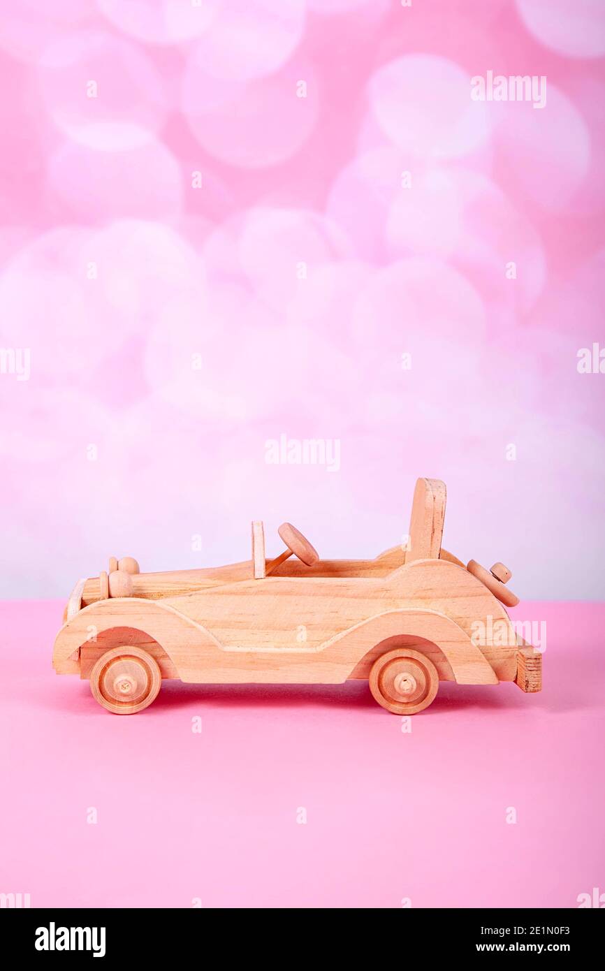 Holz Retro Auto Spielzeug auf einem rosa Hintergrund mit Bokeh Stockfoto