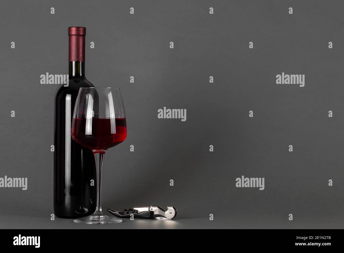 Rotweinflasche, Korkenzieher und Glas auf grauem Hintergrund. Weintrinkkultur Konzept. Leerzeichen für Text. Stockfoto