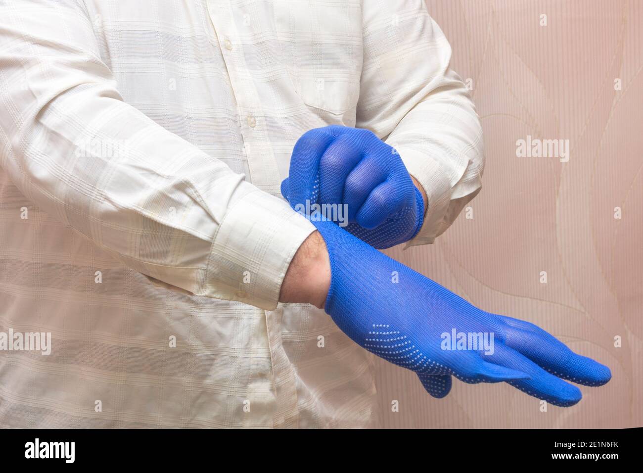 Der Mann zieht für die Arbeit blaue Stoffhandschuhe an. Handschutzkonzept, Gesundheitsschutz. Stockfoto