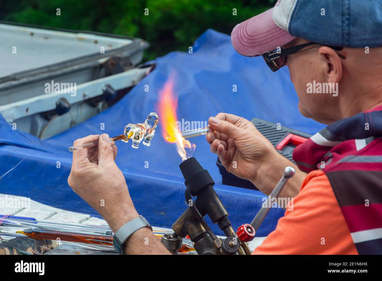 Kaliningrad, Russland - September 2020: Mann Glasbläser macht ein handgemachtes Souvenir aus Glas durch Feuer geschmolzen. Selektiver Fokus, unscharfer Hintergrund Stockfoto