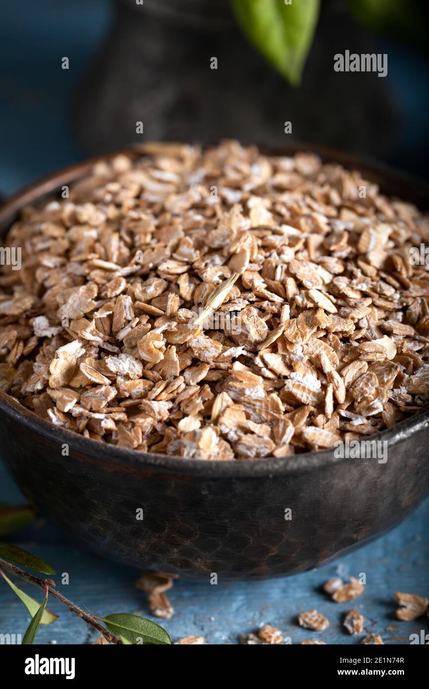 Gesunde Getreideflocken in einer Keramikschale. Roggen Flocken in einer Schüssel auf Stein blauen Holzhintergrund. Stockfoto