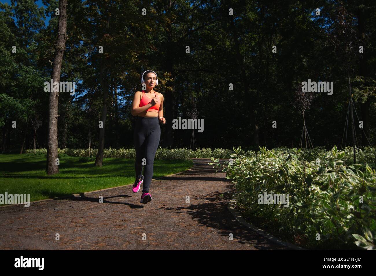 Läuferin Frau in Sportkleidung und Kopfhörer laufen auf dem Laufweg früh am Morgen. Laufen im Freien Stockfoto