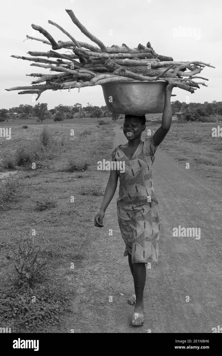 Ghanaische Mädchen des Gonja-Stammes trägt Feuerholz auf ihr Kopf Stockfoto