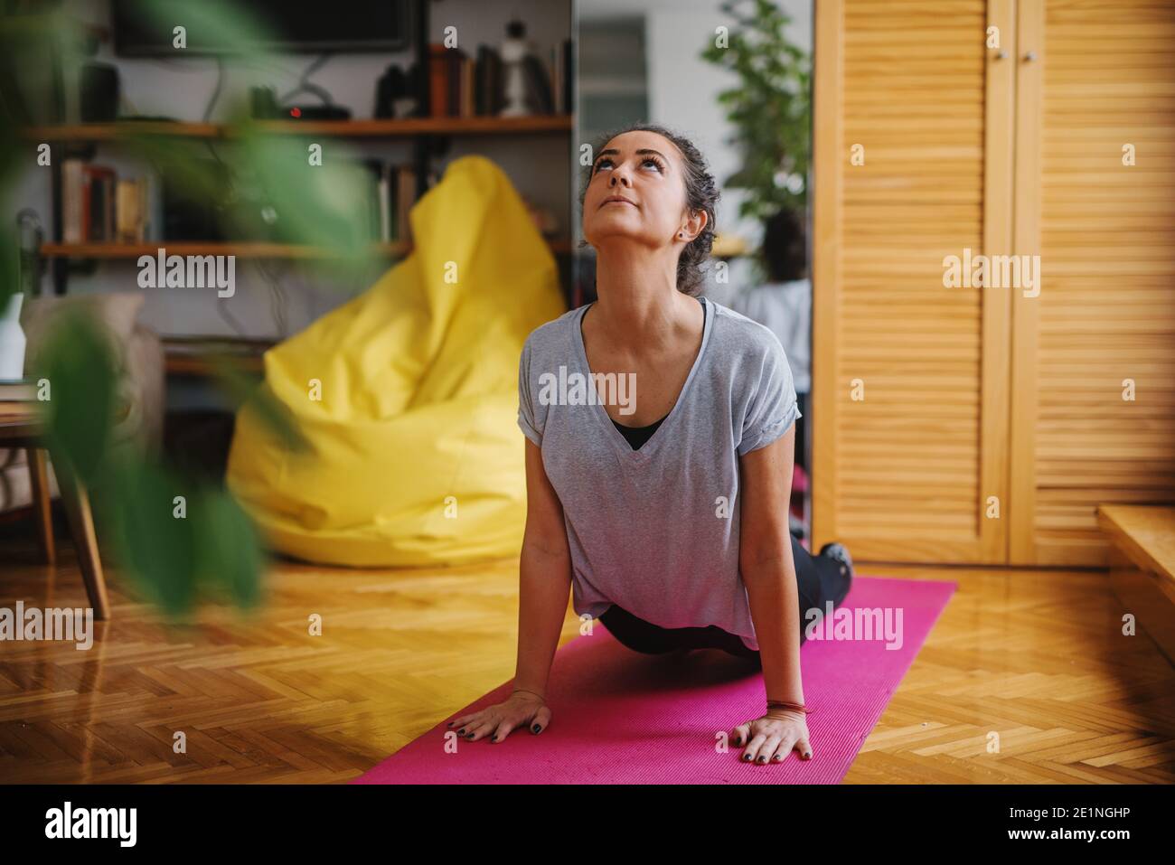 Frau macht Yoga-Übungen auf der Matte. Cobra-Pose. Wohnzimmer innen. Stockfoto
