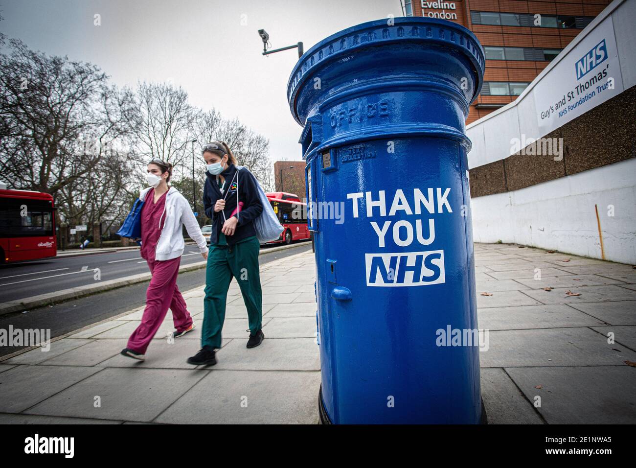 Krankenschwestern mit Gesichtsmasken kommen an einem blau gestrichenen Briefkasten vorbei und tragen die Botschaft „Thank You NHS“ vor dem St. Thomas' Hospital in London, Großbritannien Stockfoto