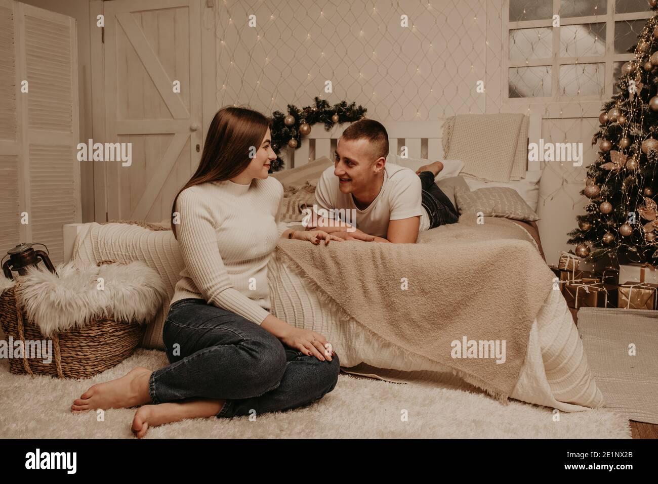 Paar Mann und Frau liegen auf Bett Schlafzimmer in der Nähe von weihnachten tree.decorated Haus für New Year.Christmas Morning. Wohnung Interieur. Valentinstag Promi Stockfoto