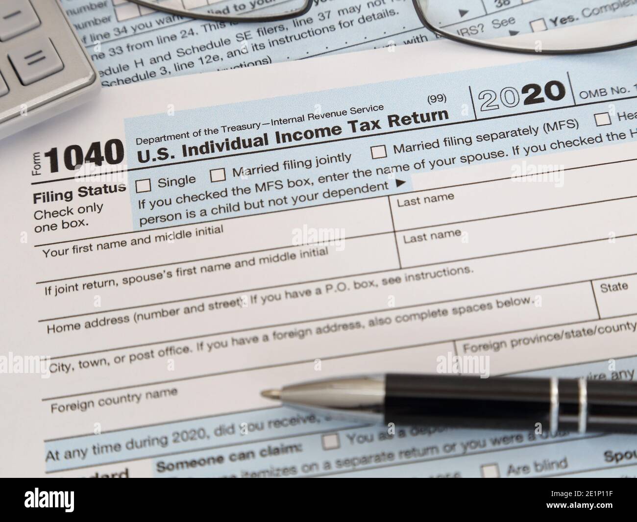 Ein USA Internal Revenue Service IRS 1040 Einkommensteuer Jahr 2020 Form wird in 2021 gezeigt, zusammen mit einem Tintenschreiber, Rechner und Gläser. Stockfoto