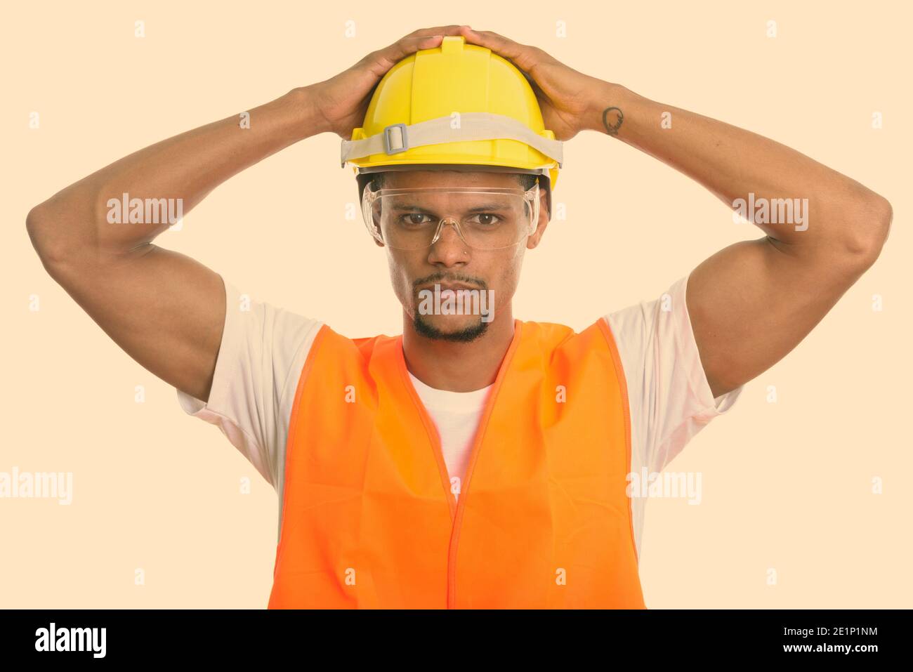 Junge afrikanische Mann Bauarbeiter mit beiden Händen am Schutzhelm Stockfoto