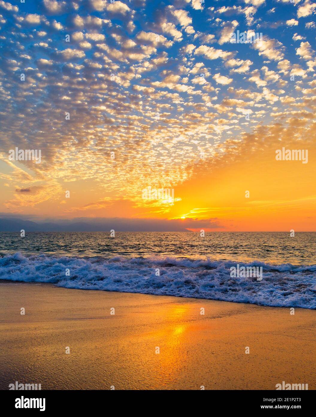 Ein farbenfroher Ocean Sunset Sky als sanfter Wave Rolls Shore in einem vertikalen Bildformat Stockfoto