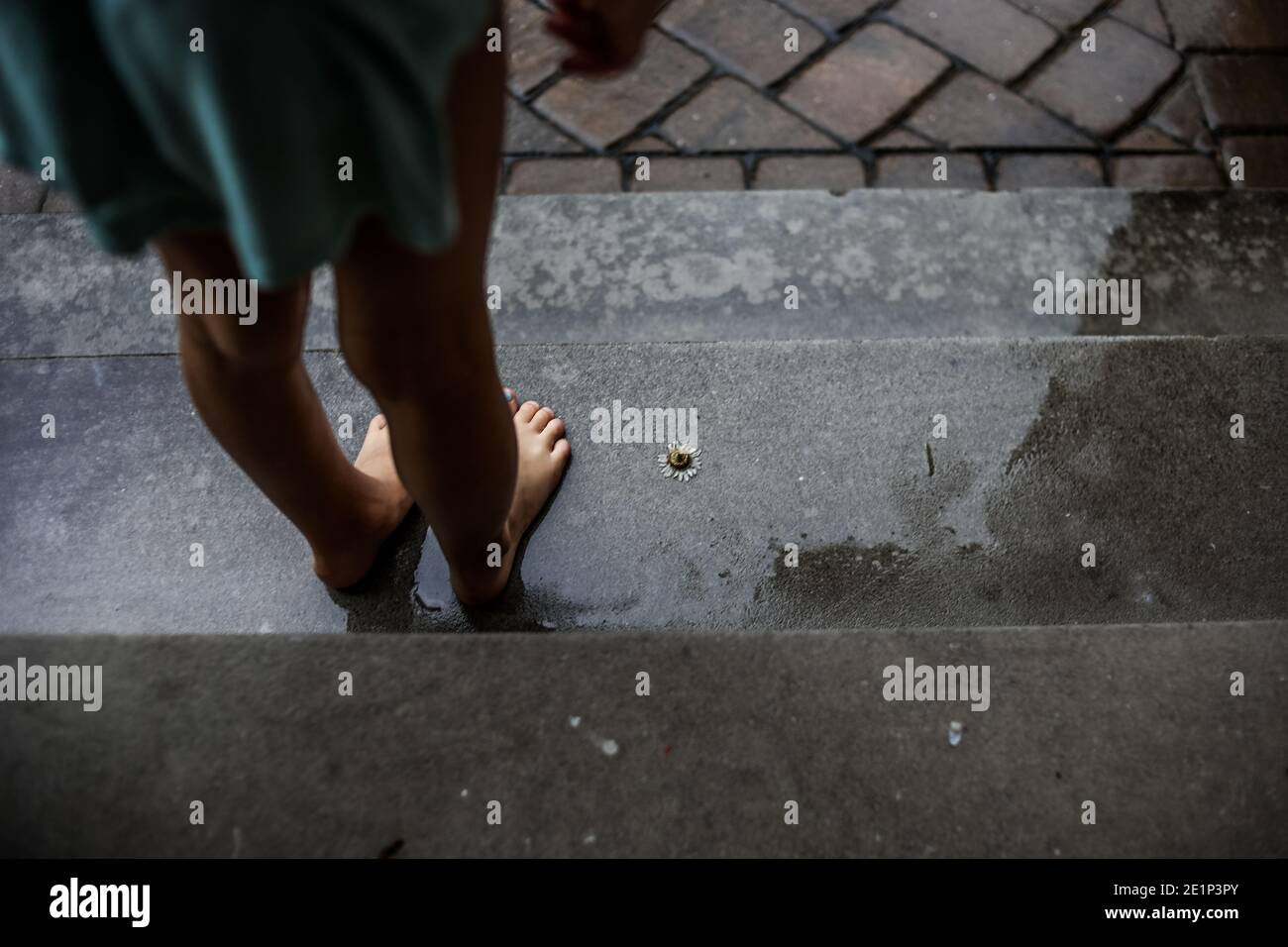 Mädchen spielt im Regen und steht auf der Treppe Stockfoto