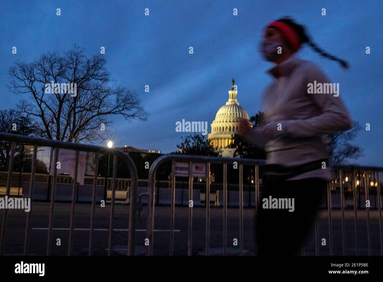 Washington, Usa. Januar 2021. Eine Frau joggt am Freitag, den 8. Januar 2021, durch Umzäunung in der Nähe des US-Kapitols in Washington, DC. Am 6. Januar brachen Trump-Mobs den Sicherheitsbereich und drangen in das US-Kapitol ein. Foto von Ken Cedeno/UPI. Kredit: UPI/Alamy Live Nachrichten Stockfoto