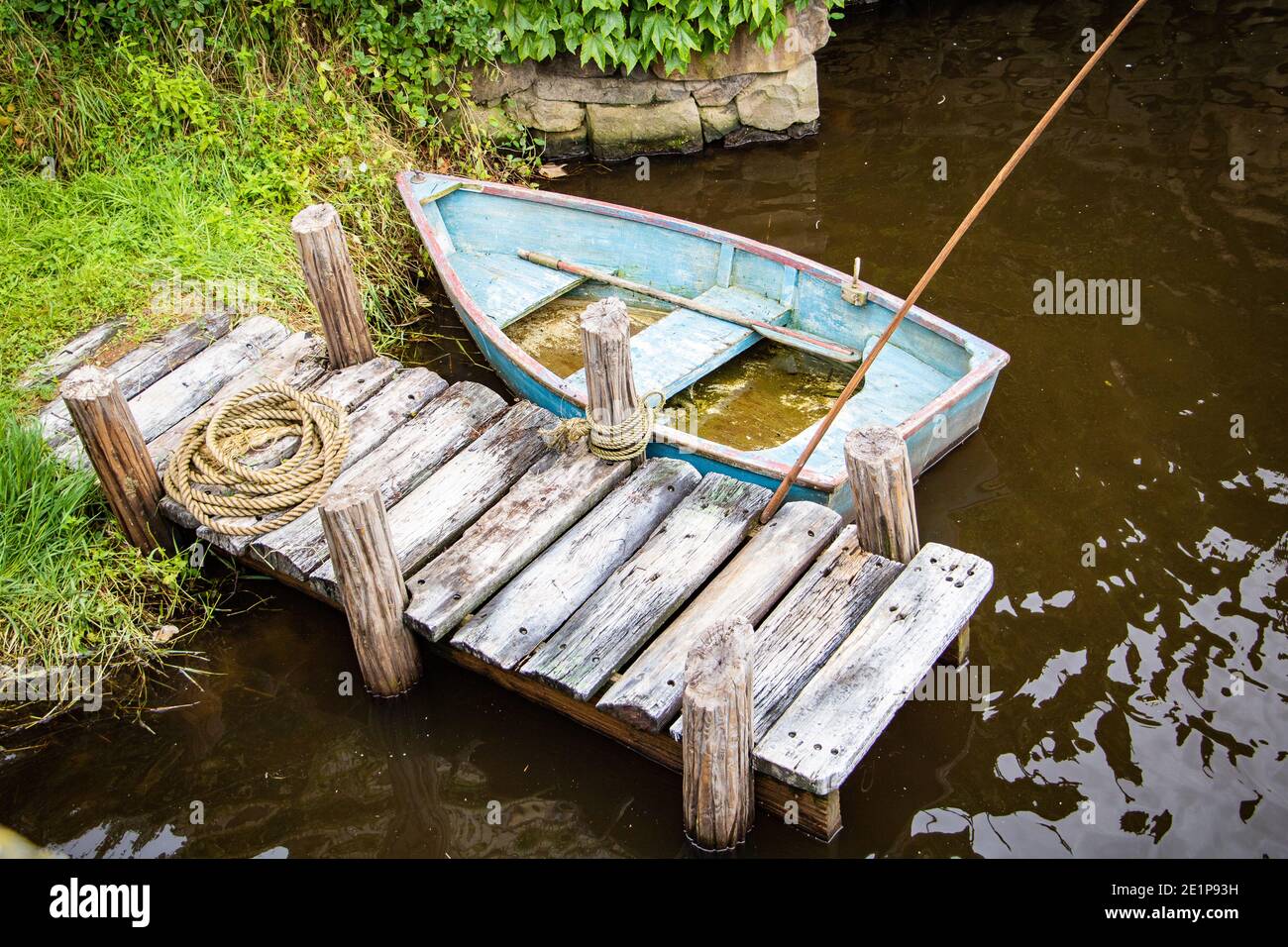 Altes verwittertes blaues Ruderboot an einem Holzsteg. Stockfoto