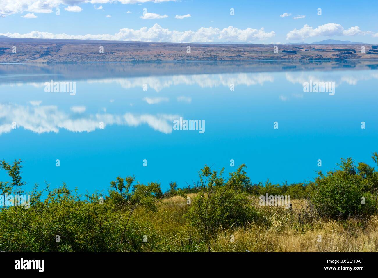 Türkisblaues Wasser des Pukaki Sees mit langer weißer Wolke Reflexionen Stockfoto