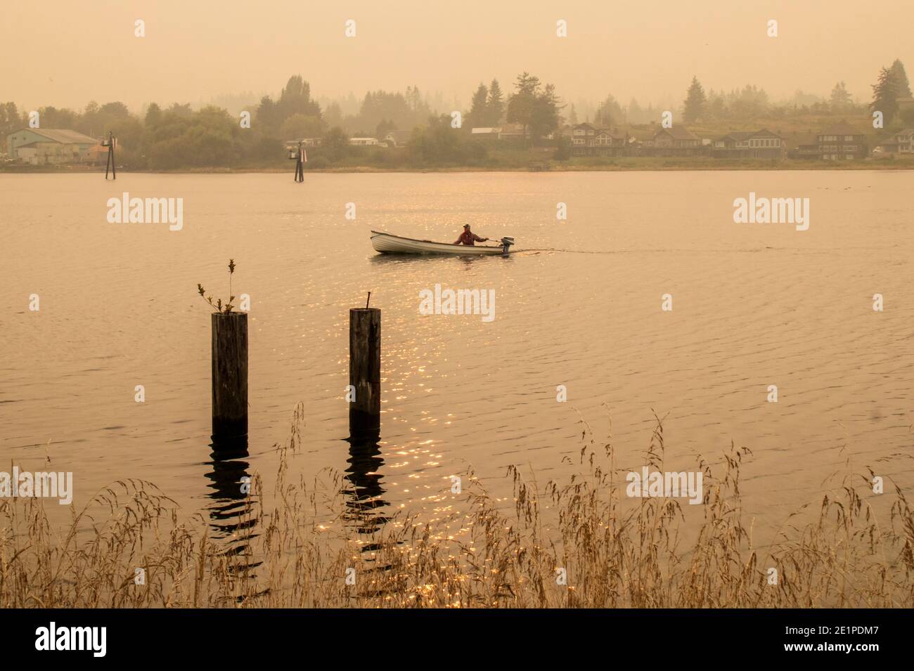 Fischer in seinem Tyee Boot auf der Campbell River Mündung, mit rauchigen Himmel von Kalifornien Waldbrände im Jahr 2020. Die Sonne und der Rauch machten rosige Farbe. Stockfoto