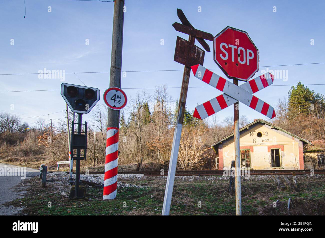 Altes rostartiges Warnschild und neues Stoppschild am unbemannten, unbemannten Bahnübergang in Bulgarien Stockfoto