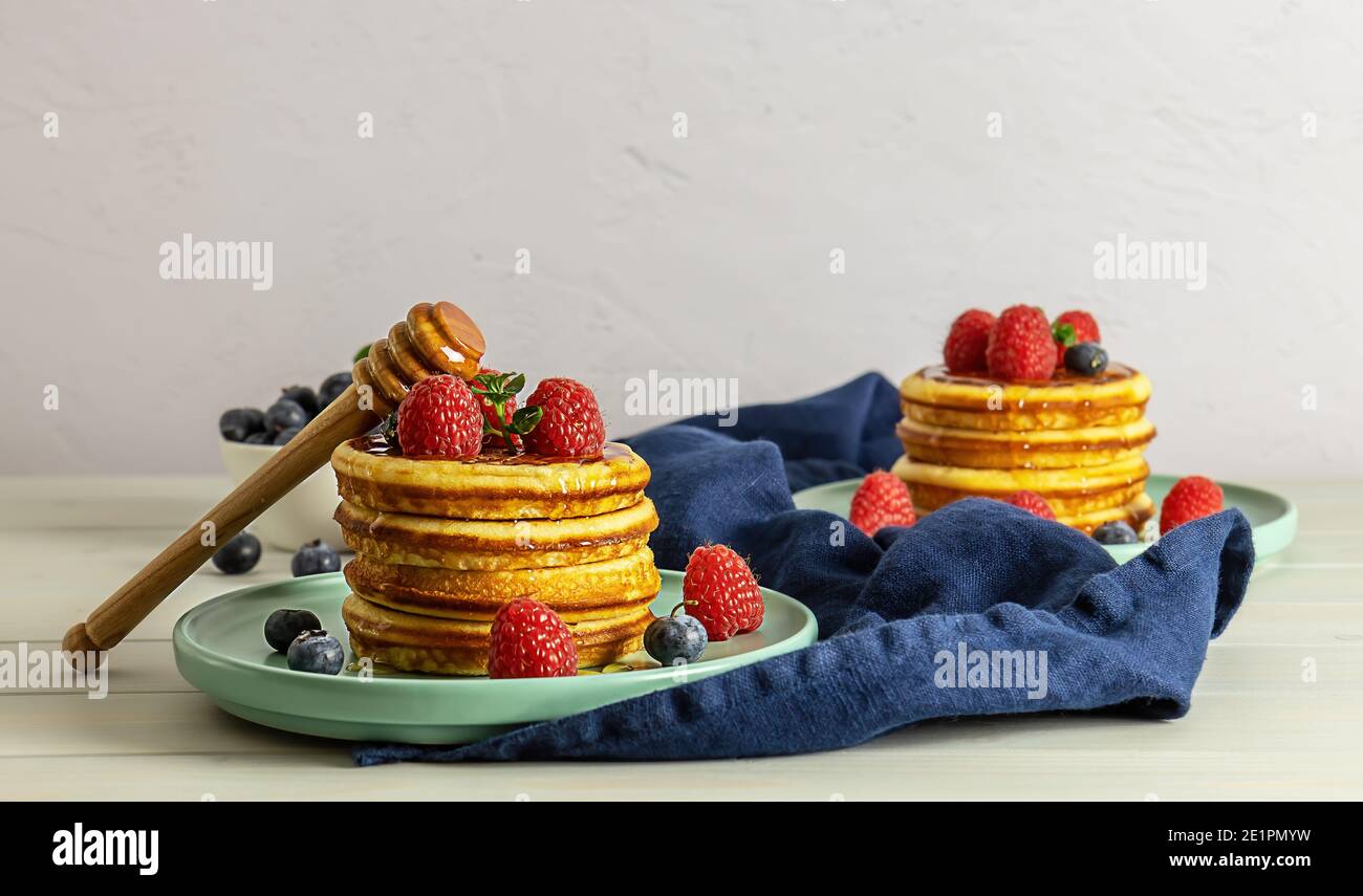 Leckere amerikanische Pfannkuchen mit Himbeeren, Heidelbeeren und Honig. Familienfrühstück-Konzept mit Kopierplatz. Stockfoto