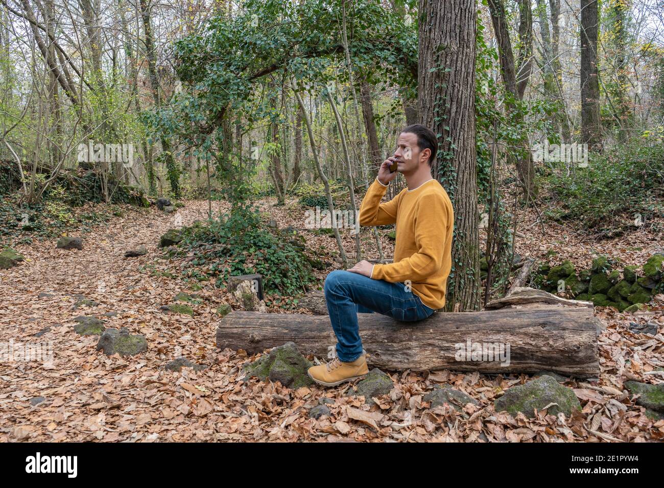 Mode Mann im Gespräch auf Handy in schönen Wald.Männlich mit Smartphone, einen Anruf Outdoor-Technologie Konzept Lifestyle. Stockfoto