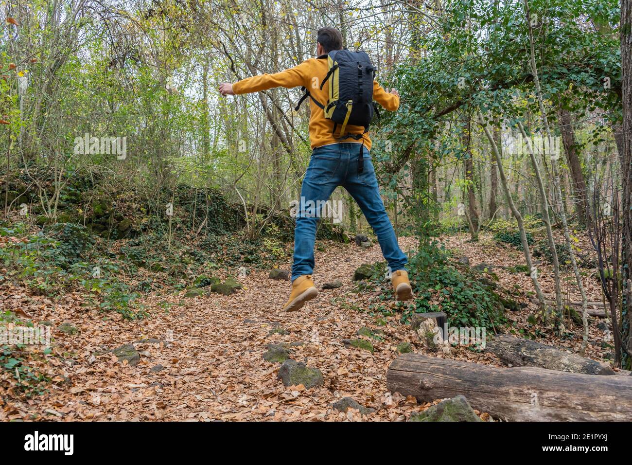 Mann mit Rucksack springen in Wald.glücklich, lustig, Freude Glück Feier Outdoor-Reise Fernweh Konzept Lifestyle. Stockfoto