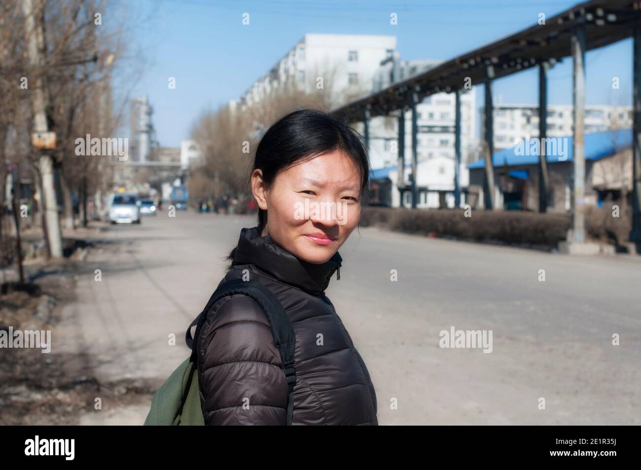 Eine lächelnde chinesin, die an einem sonnigen Frühlingstag auf den Straßen von zhaodong china in der Provinz heilongjiang unterwegs ist. Stockfoto
