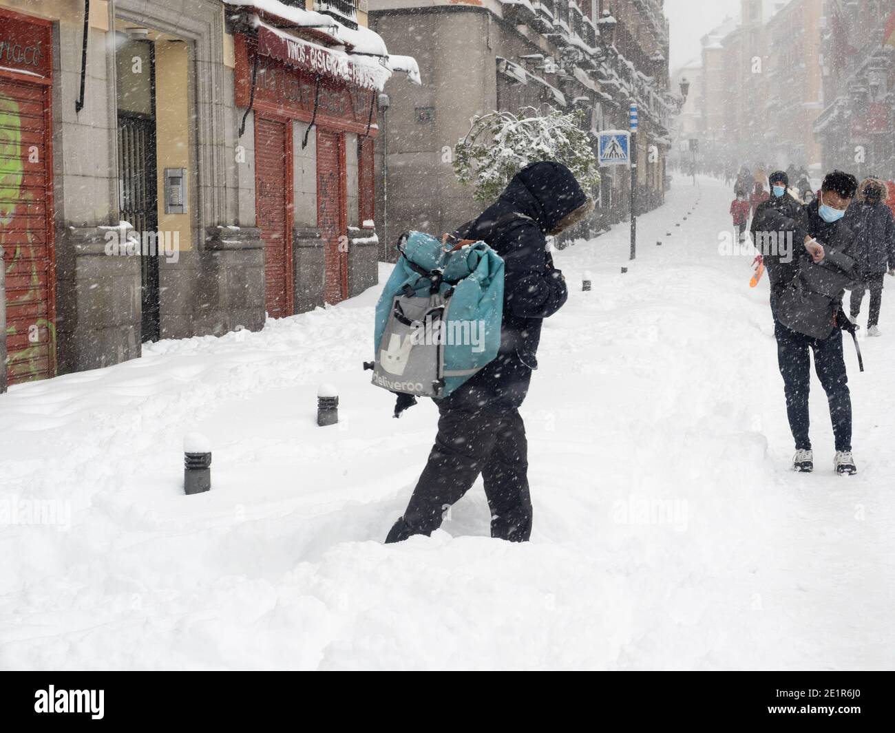 Madrid, Spanien. Januar 2021. Eine Person, die unter einem starken Schneefall mit einer Deliveroo-Tasche läuft. Sturm Filomena trifft Madrid (Spanien), ein Wetteralarm wurde für kalte Temperaturen und schwere Schneestürme in ganz Spanien ausgegeben; nach Angaben der Wetteragentur Aemet wird voraussichtlich einer der schneesichersten Tage der letzten Jahre sein. © Valentin Sama-Rojo/Alamy Live News. Stockfoto