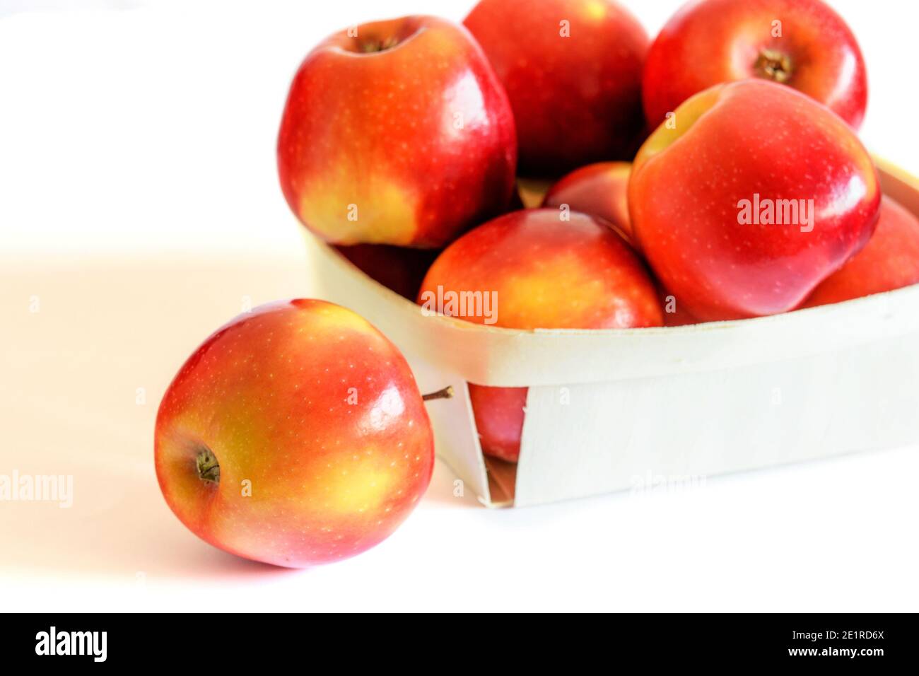 Frische rote Äpfel im Korb auf weißem Hintergrund. Gesunde vegetarische Ernährung Konzept. Stockfoto