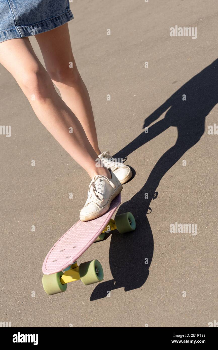Weibliche schlanke Beine auf Skateboard Nahaufnahme. Outdoor Lifestyle Bild an einem sonnigen Sommertag. Stockfoto