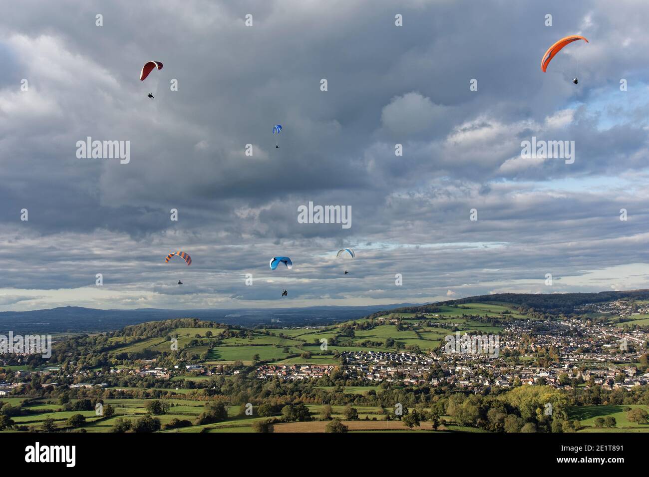 Gleitschirme fliegen von Selsley Hill, mit Stroud und Gloucester im Hintergrund, Gloucestershire, UK, Oktober. Stockfoto