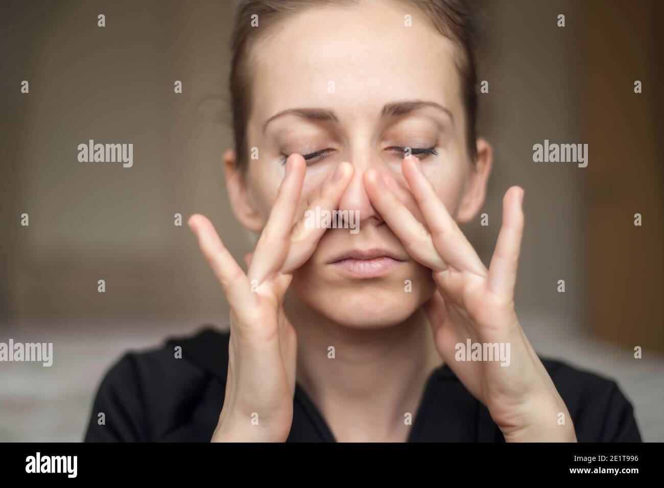 Eine junge Frau berührt ihre Nase mit ihren Fingern wegen des Verlustes ihres Geruchssinns, spürt den Geruch nicht Stockfoto