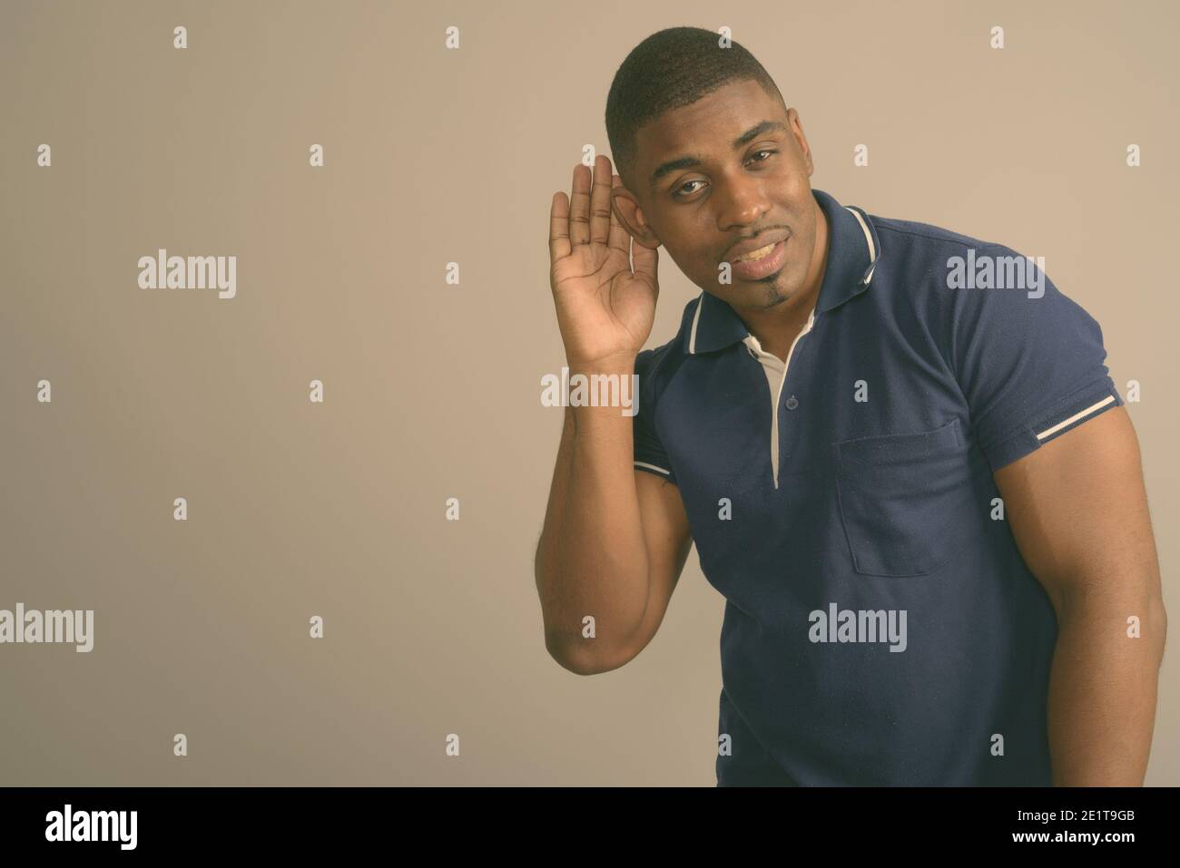 Junger schöner afrikanischer Mann trägt blaues Poloshirt gegen Grau Hintergrund Stockfoto