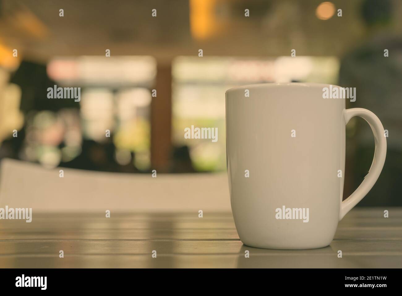Kaffeetasse auf hölzernen Tisch im Restaurant mit defokussiertem Hintergrund und bokeh Effect Stockfoto