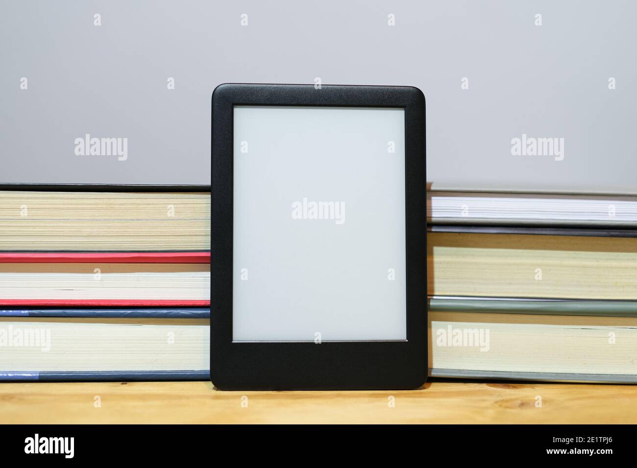 Digitaler E-Book-Reader mit klassischen Papierbüchern Hintergrund, neue Wissenstechnologien Stockfoto